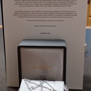 Puede incluir: Un collar con un colgante de huevo Faberg&eacute; azul turquesa, una cadena de plata y un lazo engastado con diamantes. El collar se muestra en una caja negra con el logotipo de Faberg&eacute;.