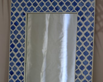 May include: A blue and white patterned mirror with a geometric design. The mirror is rectangular and has a simple frame.