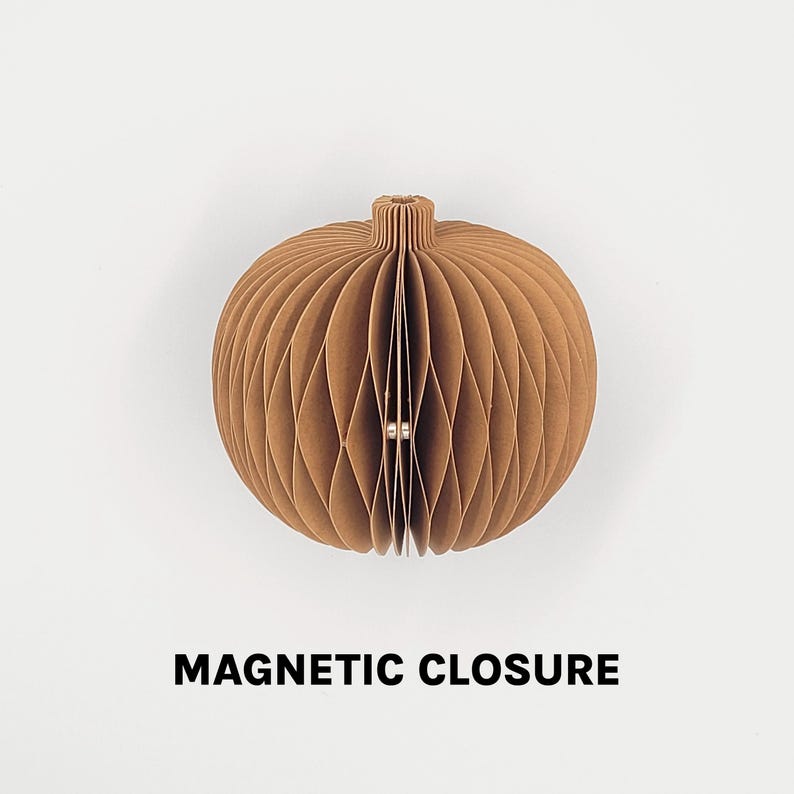 May include: A brown, spherical paper ornament with a textured, honeycomb design. The ornament has a cylindrical top and a magnetic closure. The words "MAGNETIC CLOSURE" are printed in bold, black letters below the ornament.