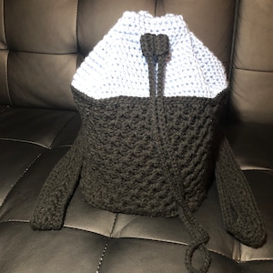 May include: A black and light blue crocheted drawstring bag with long handles.