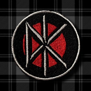 May include: Black and red embroidered patch with a stylised starburst design. The patch is circular and has a white outline.
