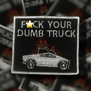 May include: Black square patch with white embroidered text "F*CK YOUR DUMB TRUCK" and a star. Below the text is a white car with flames in red and yellow. The patch has a white border.
