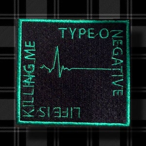 May include: A black and green embroidered patch with the text "Type O Negative" and "Life is Killing Me" in a stylized font. The patch features a green EKG line.