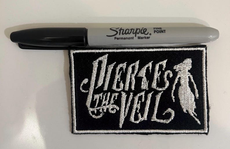May include: Black and white embroidered patch with the text "Pierce the Veil" in a stylized font. The patch features a white silhouette of a person with long hair.