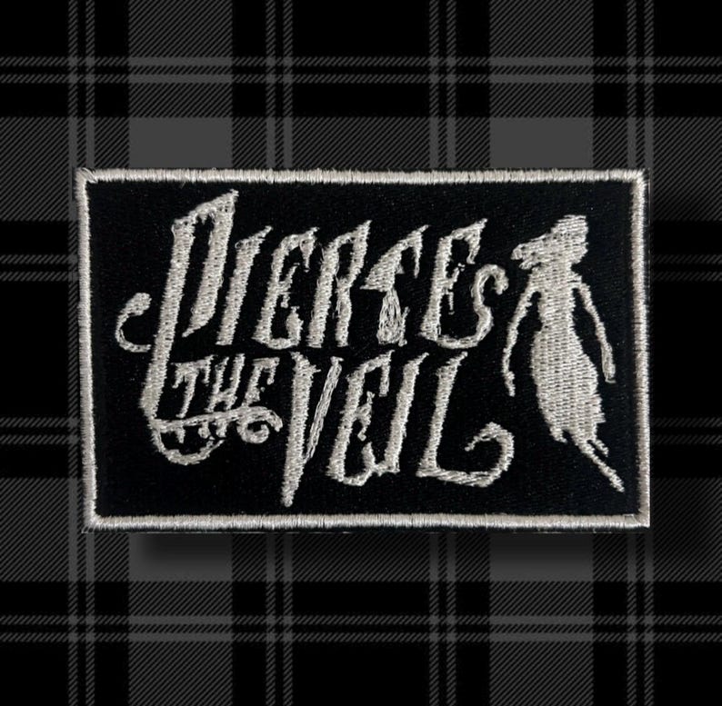 May include: A black and white embroidered patch with the text "Pierce the Veil" in a stylized font. A small, stylized figure is to the right of the text.