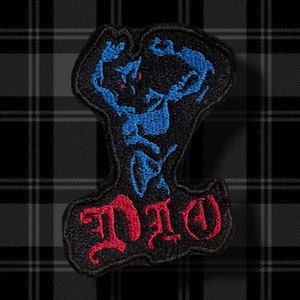 May include: Black embroidered patch with a blue and red figure and the word "DIO" in red.