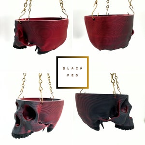 May include: Four hanging skull planters, two are black and two are red. The planters are made of a 3D printed material and have a textured surface. The planters are hanging from gold chains.