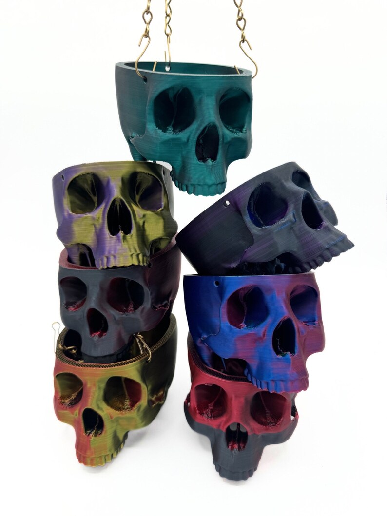 May include: A stack of six hanging skull planters in various iridescent colors, including teal, purple, black, blue, green, and red.