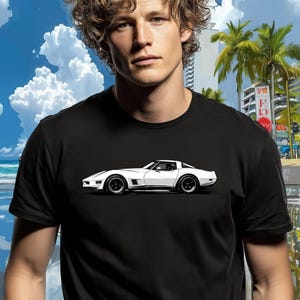 May include: Black t-shirt with a white sports car graphic. The car is a classic coupe design with black wheels and a sleek profile. The background includes a beach scene with palm trees and buildings.