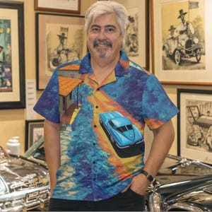 May include: A short-sleeved button-down shirt with a vibrant print featuring a blue car, a house, and a landscape of trees and sky in shades of blue, yellow, and orange. The shirt is worn by a man with gray hair and a mustache.