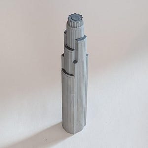 May include: A gray, detailed model of a skyscraper with a rounded top and a textured surface.