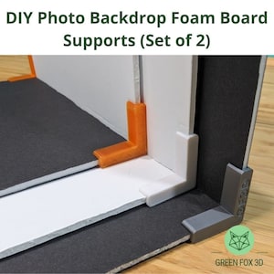 May include: Two foam board backdrop supports, one orange and one white, are attached to a black foam board. A grey corner brace is also attached to the black foam board. The text "GREEN FOX 3D" is visible in the lower right corner of the image.