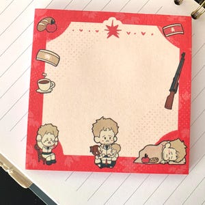 以下が含まれることがあります： 白い中心部を持つ正方形の赤い付箋。ライフル、旗、パン、コーヒー、人物の漫画イラストが特徴です。境界線には葉の模様があります。人物は悲しそうに見えます。