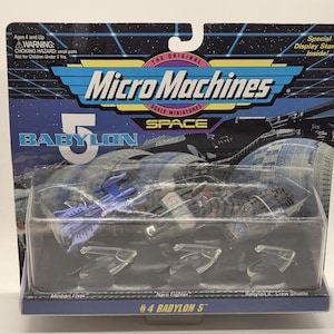 May include: Micro Machines #4 Babylon 5 scale miniatures set. The package features a blue, black, and silver color scheme with the text "Micro Machines" and "Babylon 5". The set includes a Minbari Flyer, Narn Fighter, and Babylon 5 Crew Shuttle.