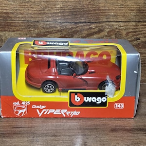 Puede incluir: Un coche de juguete Dodge Viper RT/10 rojo en su caja original. El coche de juguete es una réplica detallada con ruedas negras e interior negro. La caja presenta el logotipo de Burago y el número de modelo 4125. Aproximadamente 12 cm de largo.