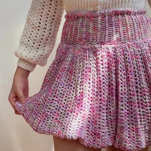 Może przedstawiać: Różowa, biała i fioletowa spódnica zrobiona na szydełku z wysokim stanem i marszczonym, falbaniastym dołem.