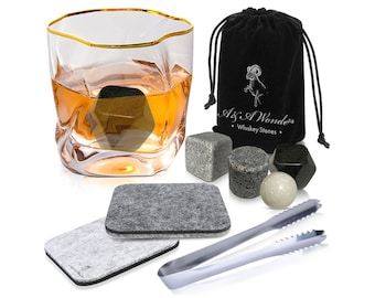 May include: Whiskey stones set with a black velvet bag, two gray coasters, a pair of silver tongs, and a glass of whiskey with a gold rim. The bag has the text "As I Wonders Whiskey Stones".