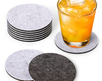 May include: A set of 10 round felt coasters in gray and black. The coasters are stacked in a pile, with a glass of orange juice on top of one of the coasters.
