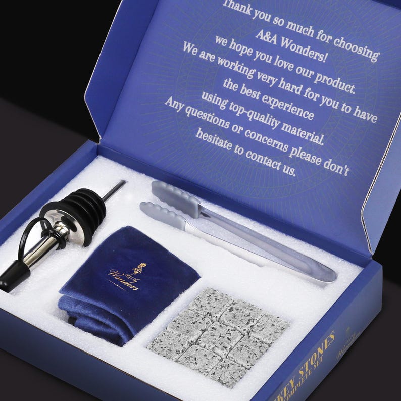 May include: A blue box with a white interior containing a set of whiskey stones, a pair of tongs, a bottle stopper, and a blue velvet bag with the words "A&A Wonders" printed on it. The box lid has the text "Thank you so much for choosing A&A Wonders! We hope you love our product. We are working very hard for you to have the best experience using top-quality material. Any questions or concerns please don't hesitate to contact us."