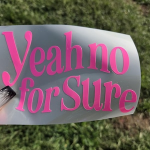May include: A vinyl decal featuring the bright pink text "Yeah no for Sure" in a bold, serif font. The lettering is applied to a clear, rectangular transfer sheet, designed for application onto smooth surfaces as a decorative adhesive graphic.