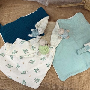 May include: Three baby blankets with crocheted turtle toys. The blankets are made of soft, textured fabric and come in teal, light blue, and white with a green leaf pattern.