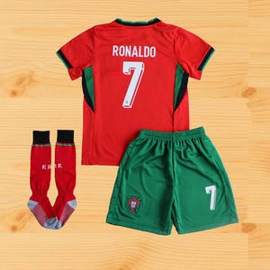 May include: A red and green soccer uniform set, featuring a jersey with "RONALDO" and the number "7" on the back, green shorts with the number "1", and red socks. The uniform has black and green accents.