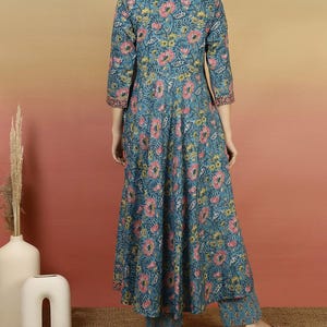 May include: A teal floral print kurta set. The long-sleeved top and matching pants feature a pattern of pink and yellow flowers. The kurta has a V-neck and a flared silhouette. The outfit is made of a lightweight fabric.