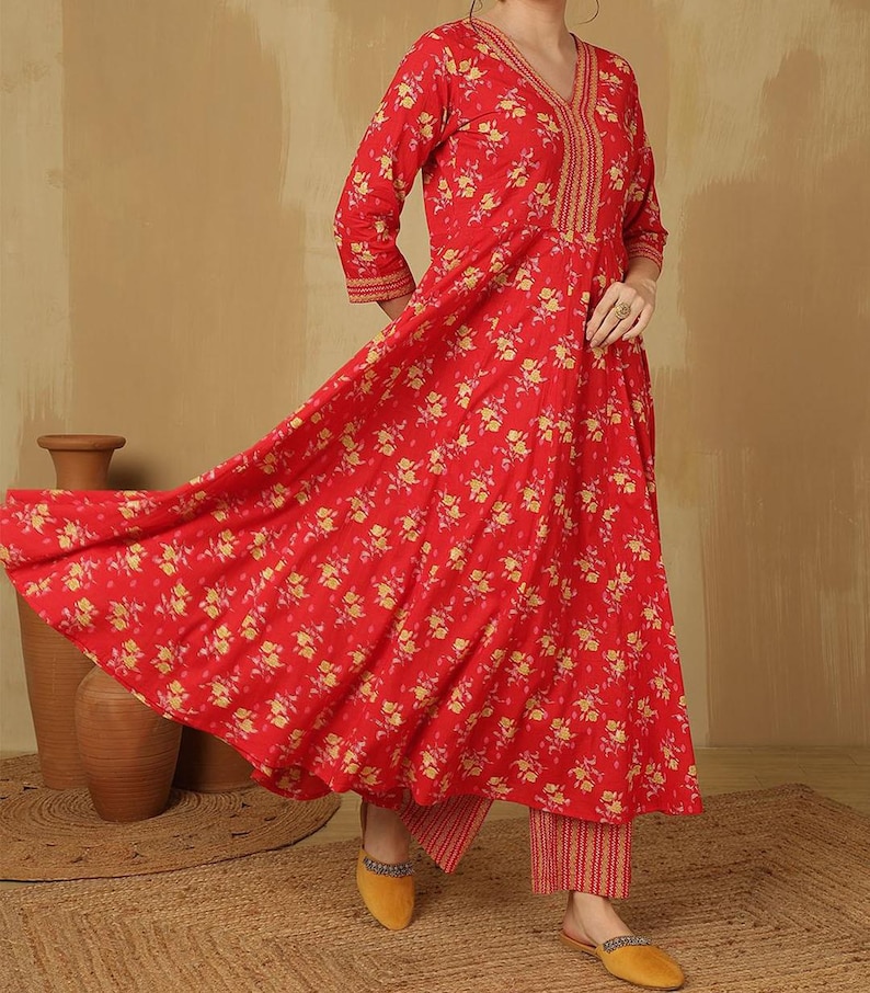 May include: A red floral print outfit featuring a long-sleeved top with a V-neck and matching pants. The top has gold embroidery around the neckline and cuffs. The outfit is paired with yellow shoes.