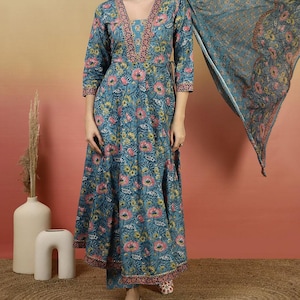 May include: A teal floral print dress with a matching scarf. The dress features a V-neckline and three-quarter sleeves. The floral pattern includes pink and yellow flowers. The outfit is paired with matching pants and shoes.