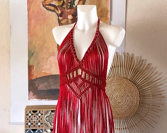 May include: A red crocheted halter top with fringe detailing. The top is made of a soft, lightweight yarn and has a relaxed, bohemian style.