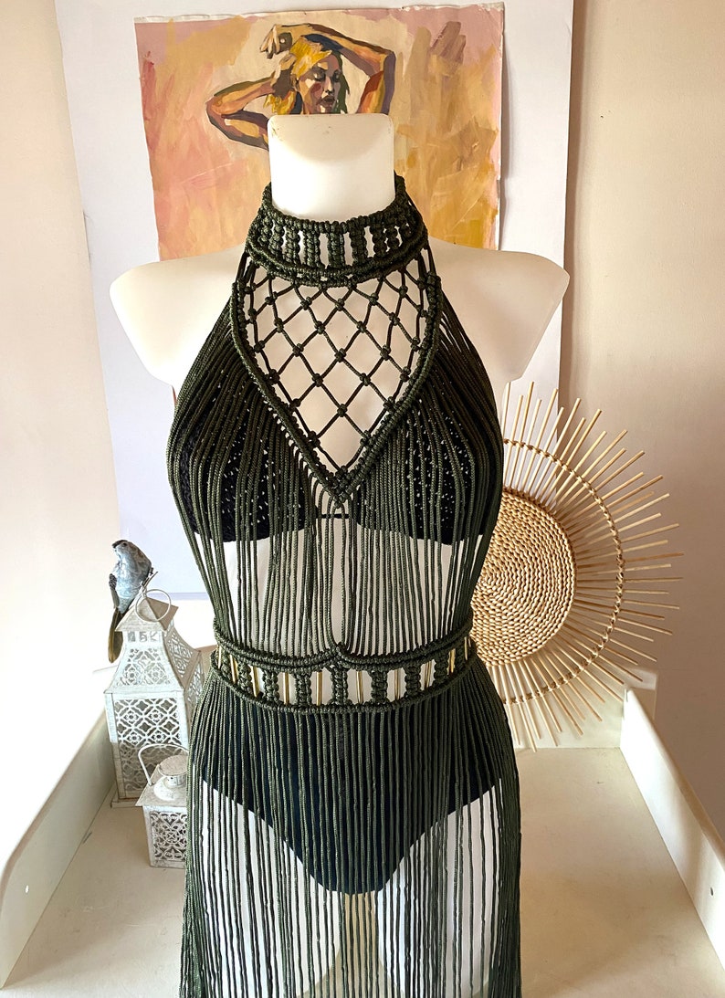 May include: A green macrame halter top with a fringe skirt. The top has a geometric design and the skirt is long and flowing.