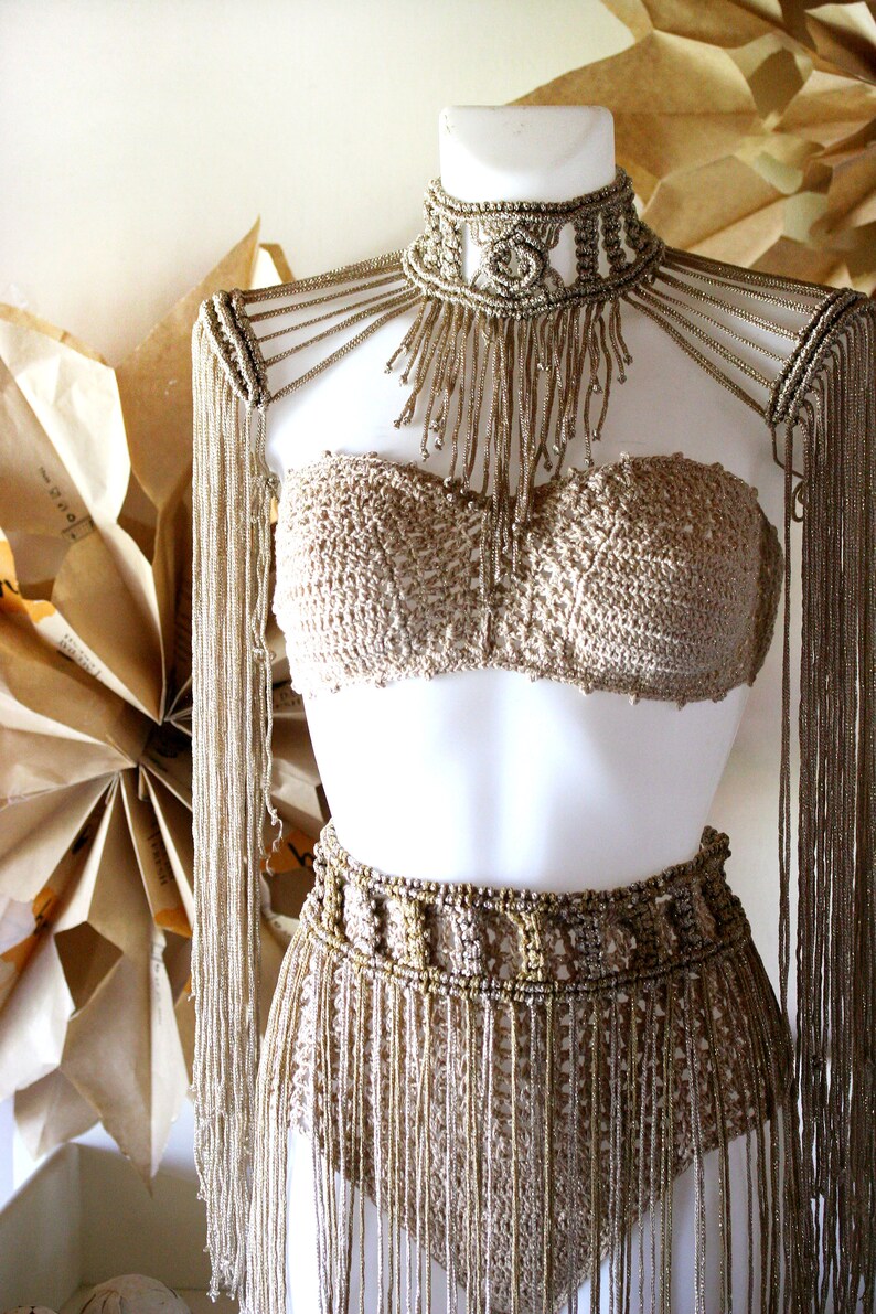 Op de afbeelding: Een gouden haltertop en rokset met franjes. De top is een bandeau-stijl en de rok is een hoge taille, aansluitende stijl.
