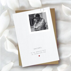 Puede incluir: Una tarjeta de felicitaci&oacute;n blanca con una foto en blanco y negro de una pareja abraz&aacute;ndose. La tarjeta dice "RACHEL To my amazing Wife on Valentines Day" con un peque&ntilde;o coraz&oacute;n rojo. La tarjeta est&aacute; sobre un sobre marr&oacute;n.