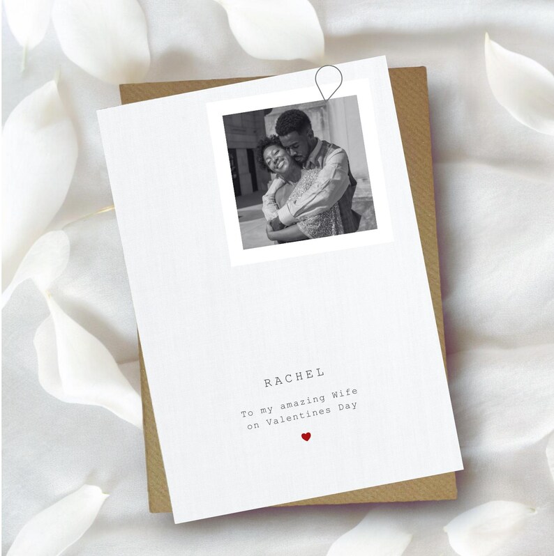 Puede incluir: Una tarjeta de felicitaci&oacute;n blanca con una foto en blanco y negro de una pareja abraz&aacute;ndose. La tarjeta dice "RACHEL To my amazing Wife on Valentines Day" con un peque&ntilde;o coraz&oacute;n rojo. La tarjeta est&aacute; sobre un sobre marr&oacute;n.