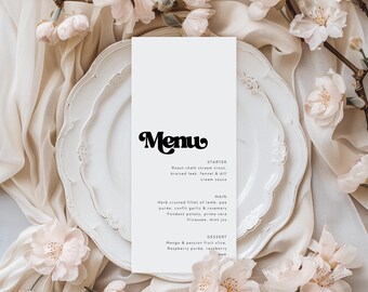 May include: A white menu card with the word "Menu" in a bold, decorative font. The menu is placed on a white plate with a decorative edge, surrounded by soft fabric and delicate pink flowers. The menu lists starter, main, and dessert options.