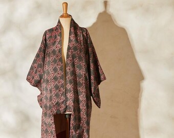 May include: A long, black and pink patterned robe with a geometric design. The robe is displayed on a mannequin.