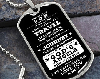 May include: Black and silver dog tag necklace with a prayer for a son to travel safely. The text reads "Prayer to my son down all the highways that you travel blacktop, stone and even gravel. On every journey through & through May God's Angels ride with you Drive safe Love you always."