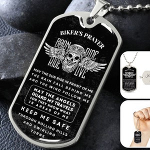 May include: Black and silver biker's prayer dog tag necklace with a skull and wings design. The tag reads "Born to Ride to Live" and "May the sun rise in front of me, the rain fall behind me, and the wind follow me. May the angels guard my travels for they know what is ahead of me. Keep me safe through rolling hills and swirling turns."