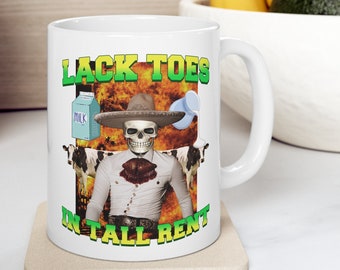 Può includere: Tazza in ceramica bianca con uno scheletro con sombrero e abito da charro. La tazza presenta il testo "LACK TOES IN TALL RENT" in verde e giallo. Sono raffigurati anche un cartone di latte e delle mucche.