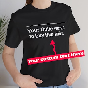 Puede incluir: Camiseta negra con texto blanco que dice "Your Outie wants to buy this shirt." Una flecha apunta hacia arriba a una barra roja con el texto "Your custom text there".