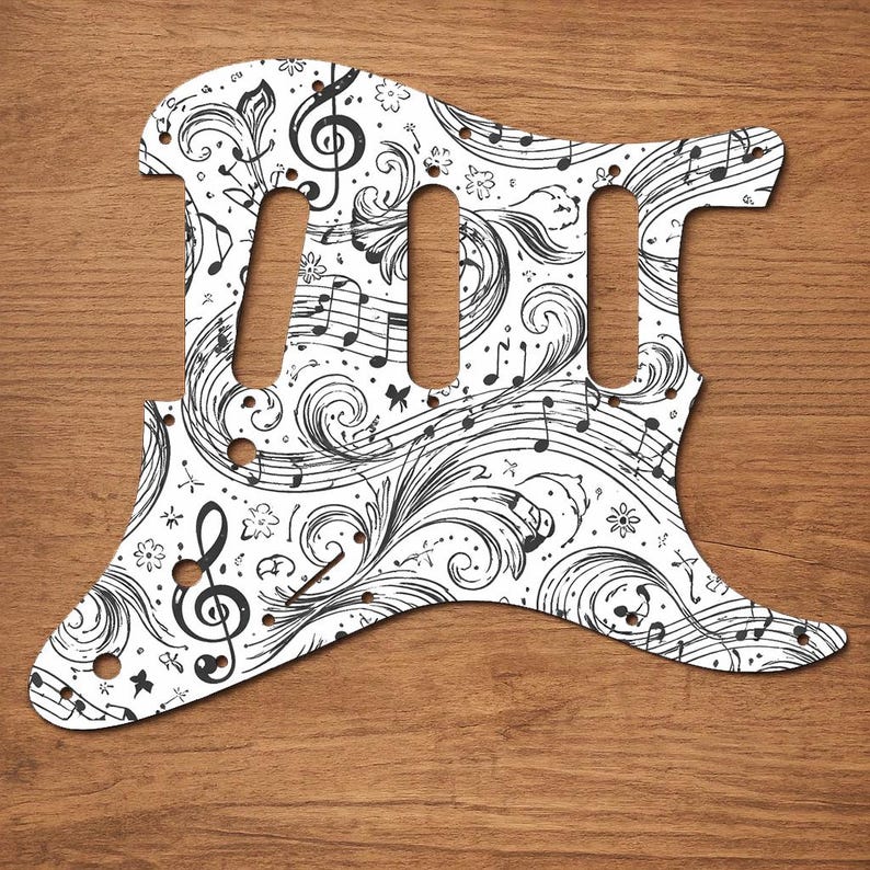 Puede incluir: Golpeador de guitarra blanco con un dise&ntilde;o floral y de notas musicales en negro. El golpeador tiene tres recortes para pastillas y varios agujeros para tornillos. El dise&ntilde;o incluye claves de sol, notas musicales y patrones ondulados.