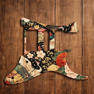 May include: A guitar pickguard featuring a Japanese floral design. The pickguard is black with a pattern of flowers, cranes, and a fan. The pickguard is shaped like a stylized letter.