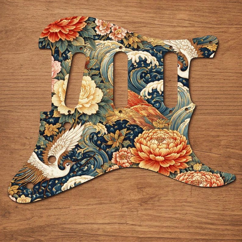 Puede incluir: Un golpeador de guitarra con un dise&ntilde;o floral y de olas. El dise&ntilde;o presenta grandes flores naranjas y amarillas, p&aacute;jaros blancos y olas azules sobre un fondo azul oscuro. Tiene tres recortes para pastillas.