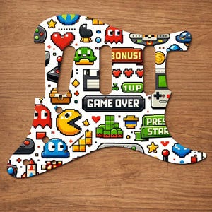 Puede incluir: Un golpeador de guitarra blanco con un dise&ntilde;o de videojuego pixelado y colorido. El dise&ntilde;o incluye Pac-Man, corazones, fantasmas y las palabras "GAME OVER", "BONUS!", "1UP" y "PRESS START".