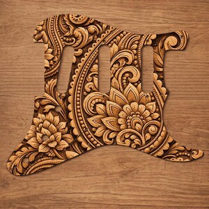 Puede incluir: Un golpeador de guitarra de madera con intrincados tallados florales y de volutas. El golpeador es de color marr&oacute;n claro y presenta tres recortes para pastillas. El dise&ntilde;o es detallado y parece estar tallado a mano.