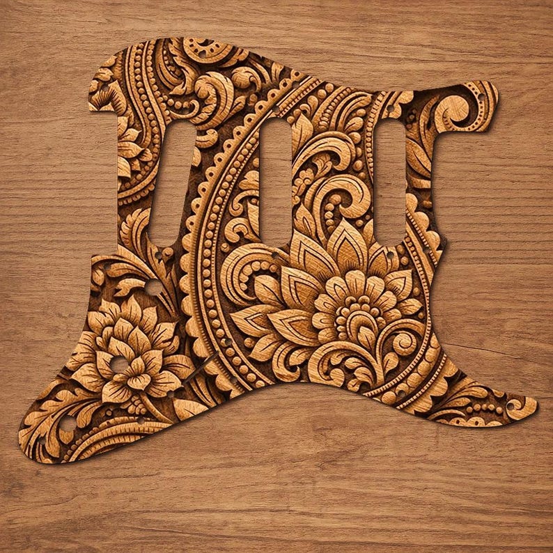 Puede incluir: Un golpeador de guitarra de madera con intrincados tallados florales y de volutas. El golpeador es de color marr&oacute;n claro y presenta tres recortes para pastillas. El dise&ntilde;o es detallado y parece estar tallado a mano.