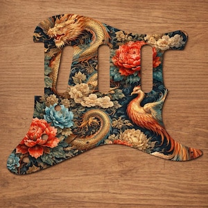 Könnte beinhalten: Ein Gitarren-Schlagbrett mit einem detaillierten floralen und mythischen Kreaturen-Design. Das Schlagbrett zeigt einen goldenen Drachen, einen Phönix und verschiedene Blumen in Rot-, Blau- und Cremetönen vor einem dunkelblauen Hintergrund. Das Schlagbrett ist auf einer Holzoberfläche platziert.