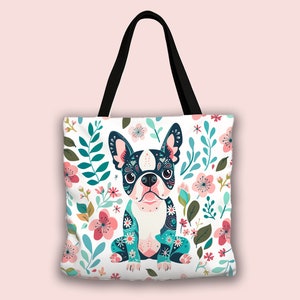 Puede incluir: Una bolsa de tela blanca con asa negra presenta una ilustraci&oacute;n colorida de un perro Boston Terrier rodeado de flores rosas, azules y verdes.