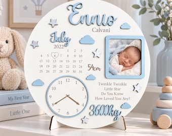 Peut inclure: Une plaque de naissance ronde en bois blanc avec le nom Ennio Calvani, un calendrier de juillet 2022 avec un cœur sur le 6, une horloge, un cadre photo avec un bébé et le texte 54cm, 3600kg et Twinkle Twinkle Little Star.