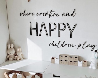 May include: A white wall with black wooden letters spelling "where creative and happy children play". There are two white stuffed bunnies on a white table in front of the wall. There are also small brown boxes with white bear faces on them.